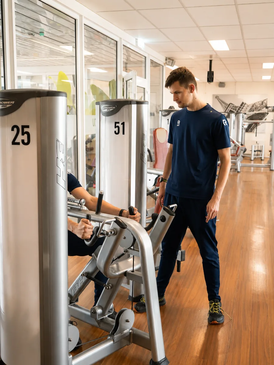 Coach van Club You Alblasserdam bij een krachtapparaat